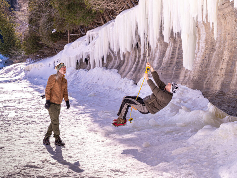 Quebec River Rope Swing Friends enjoying a swing rope on a sunny winter day on the Samuel Champlain River in Quebec.