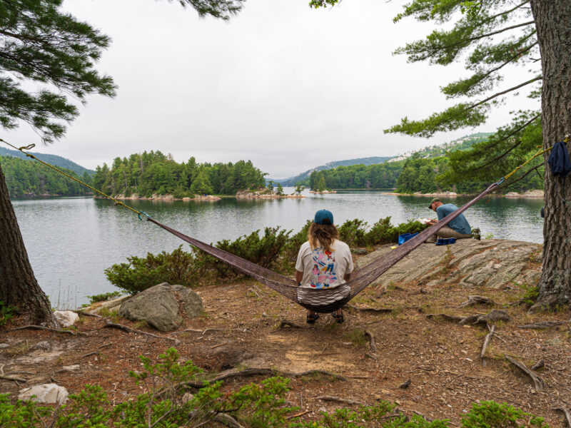 Overcast Killarney Lake Site Girl sits on hammock looking out over Killarney Lake on an overcast summer morning.